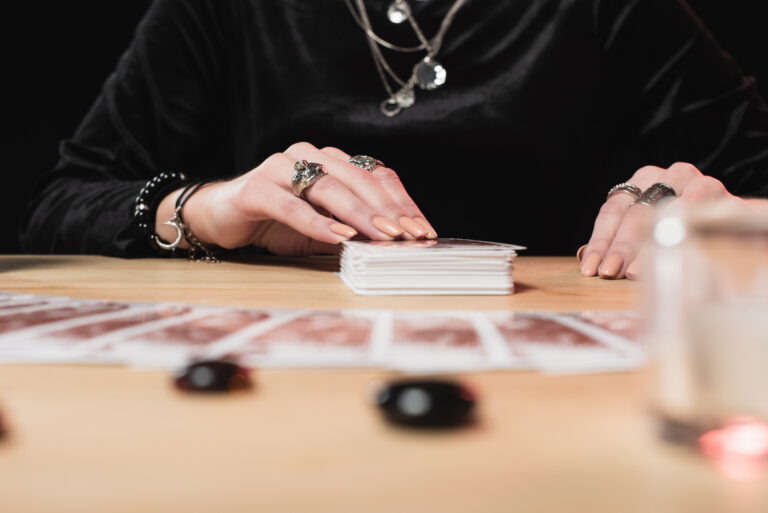 selective focus of  female psychic laying tarot cards near divination stones